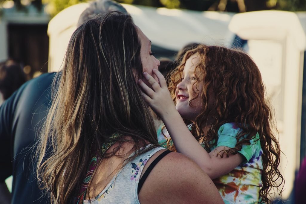 woman carrying girl while showing smile