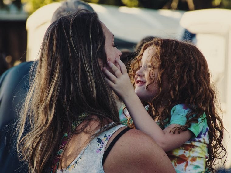 woman carrying girl while showing smile