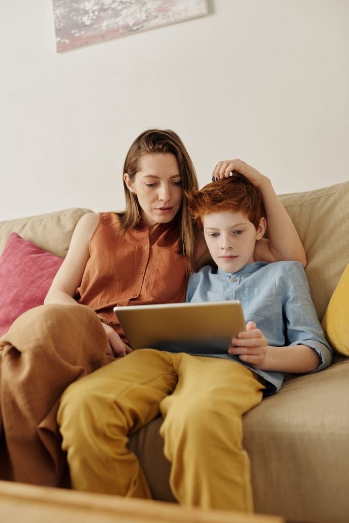 photo of woman and boy watching through tablet computer