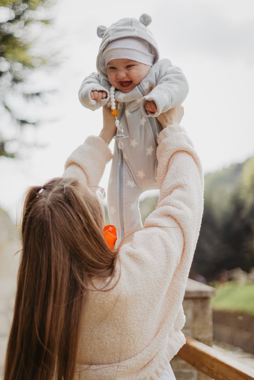 woman raising baby up - masking Autistic and ADHD Girls In Early Childhood