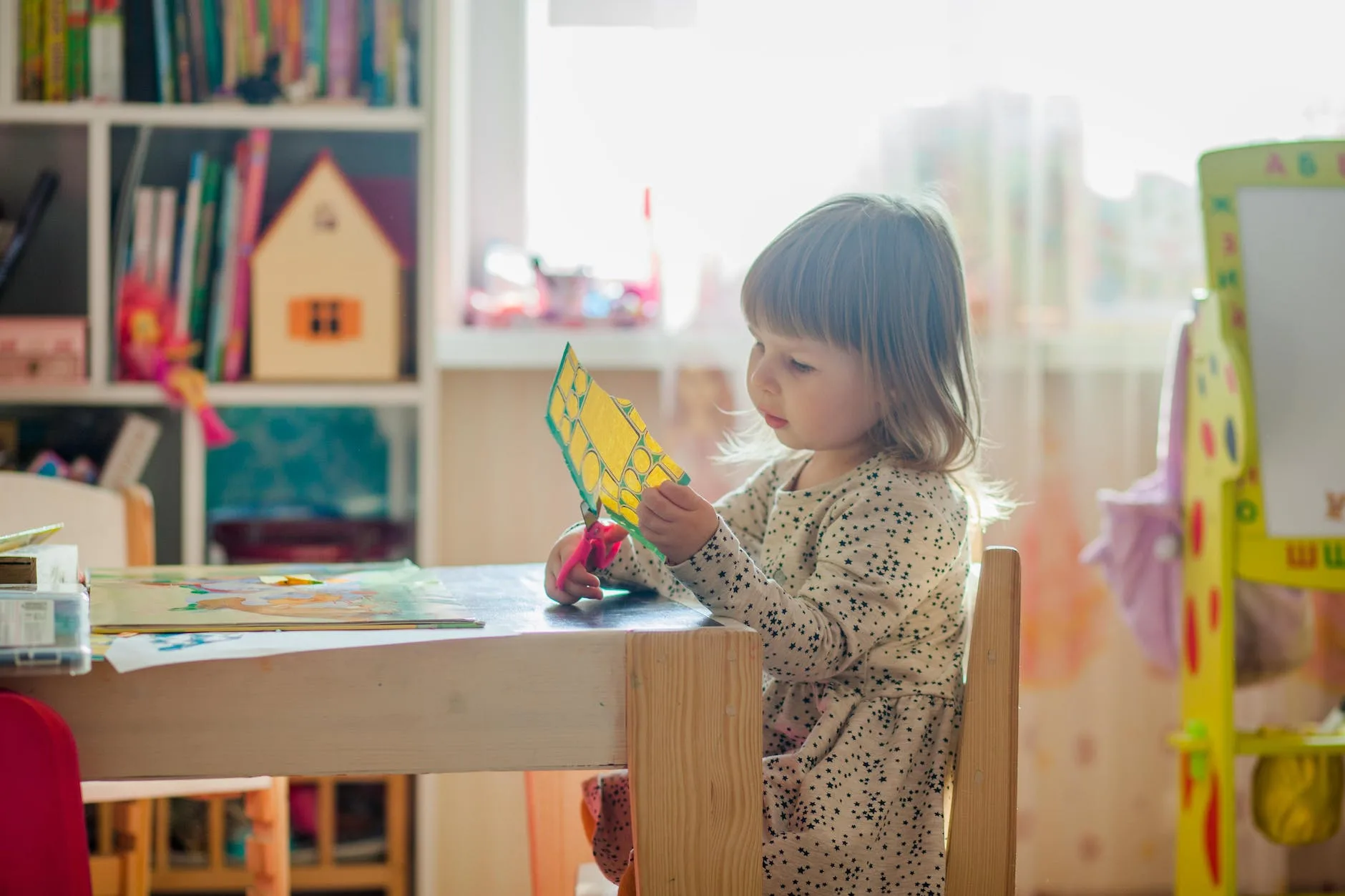 girl in white long sleeve dress sitting on brown wooden chair cutting paper -
Autistic and ADHD Girls In Early Childhood