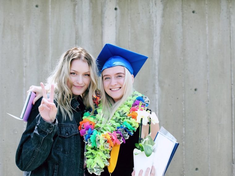 woman wearing blue mortarboard cap standing near woman wearing blue jacket