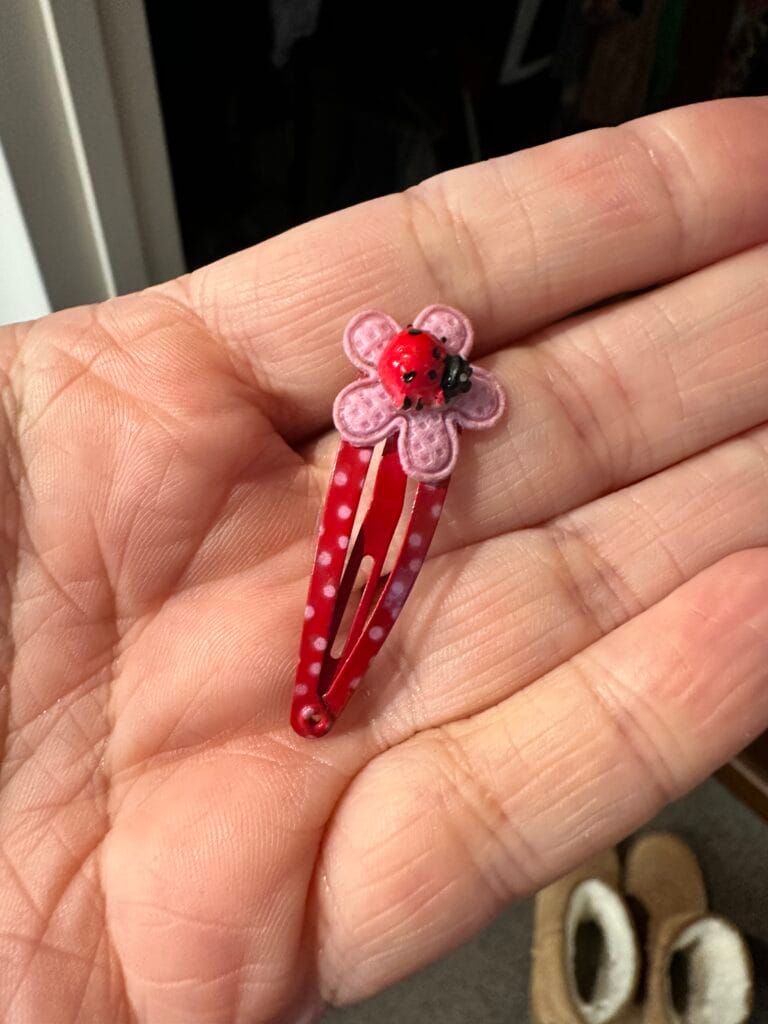 Mother holding a toddler’s hairclip with tears in her eyes – symbol of parenting grief and memories
