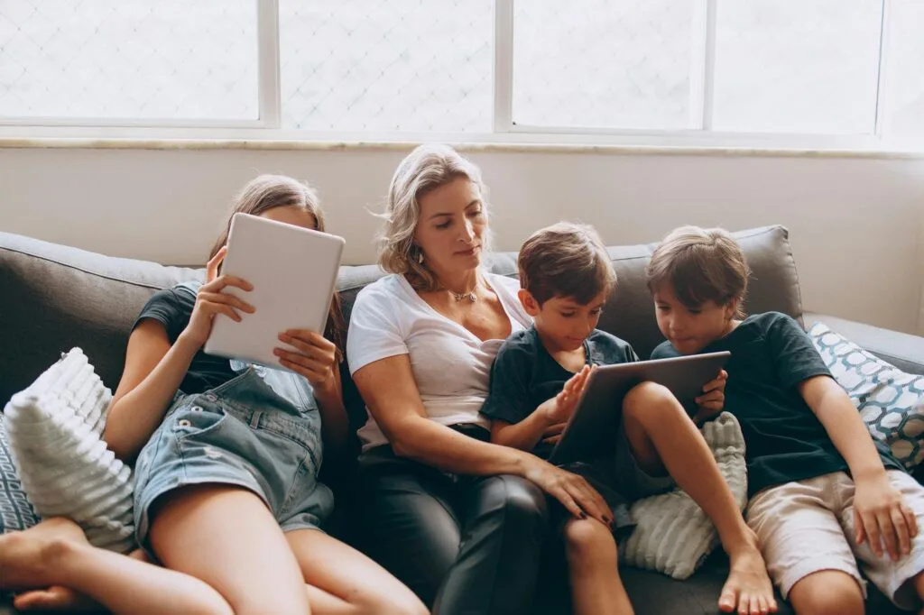 Mother and children with tablets on the couch Autistic Burnout Parent Support