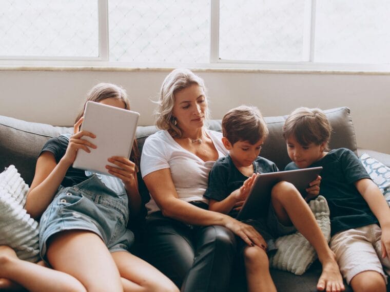 family relaxing on sofa with tablets at home
