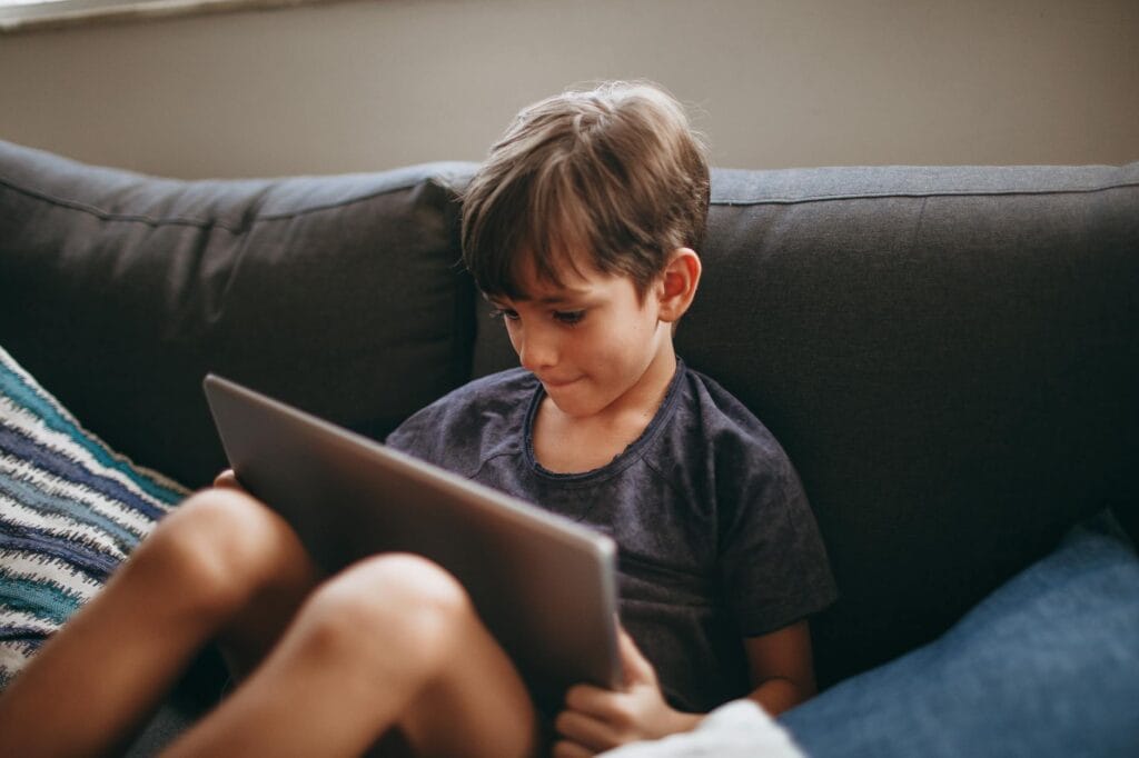 young boy engaging with tablet on cozy sofa Autistic Burnout Community for Parents