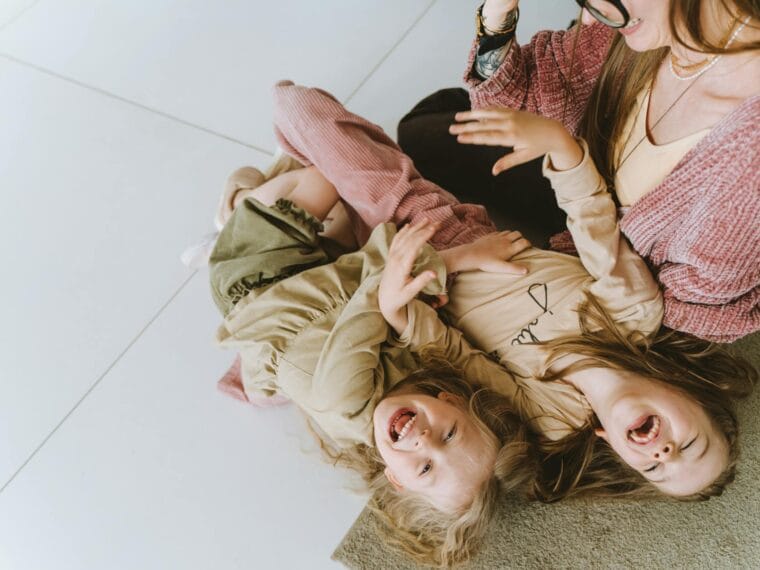 photo of siblings laughing beside their mother