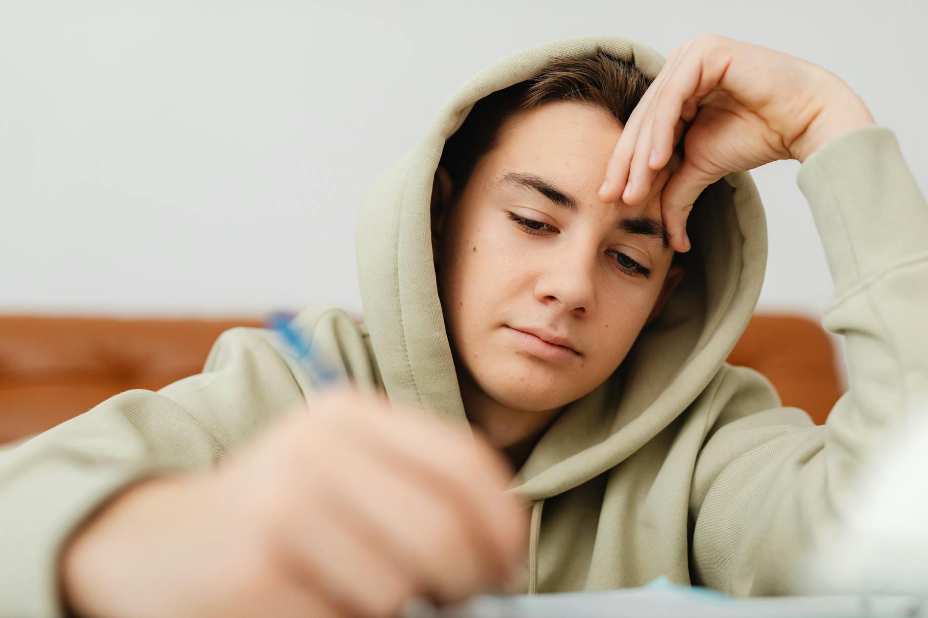 close up photo of a tired boy with his hand on his forehead
