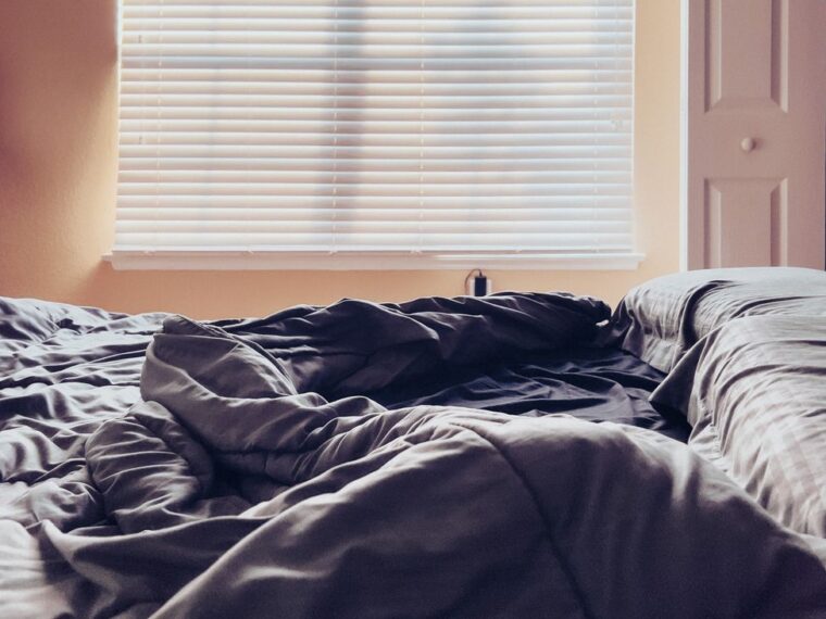 empty bed with sheets in home bedroom