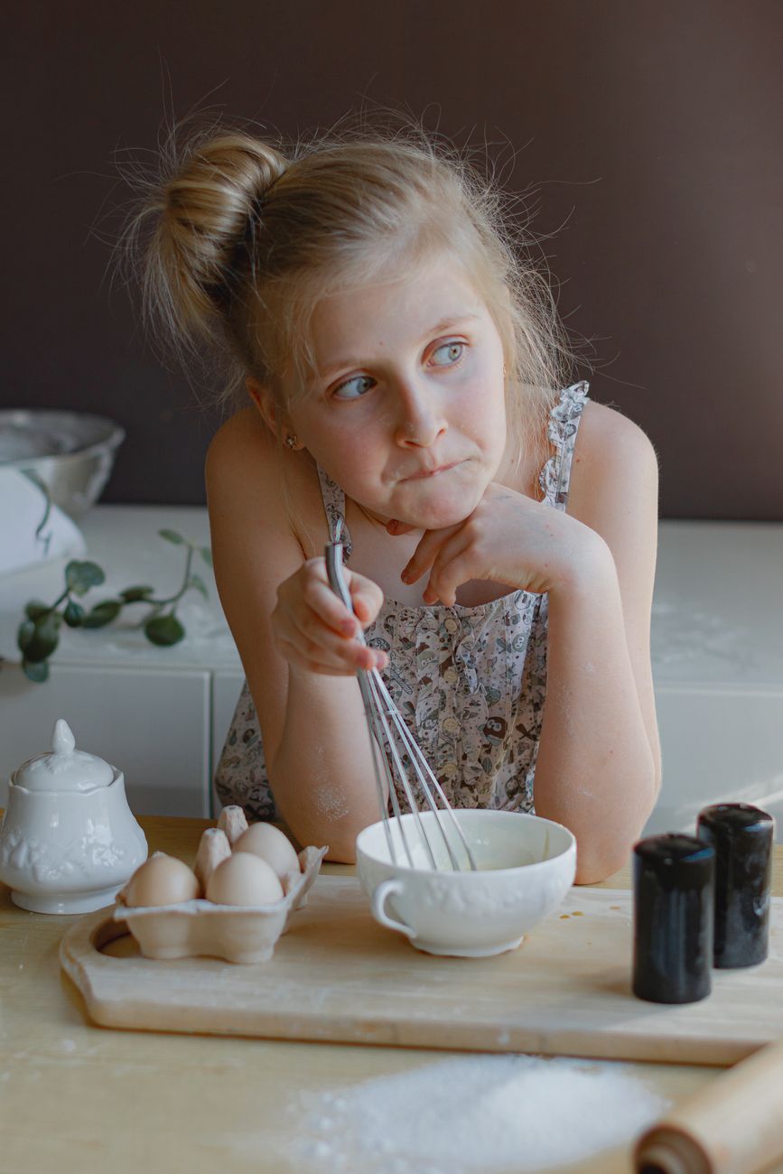 young girl baking in a cozy kitchen setting - low demand parenting for neurodivergent child in burnout